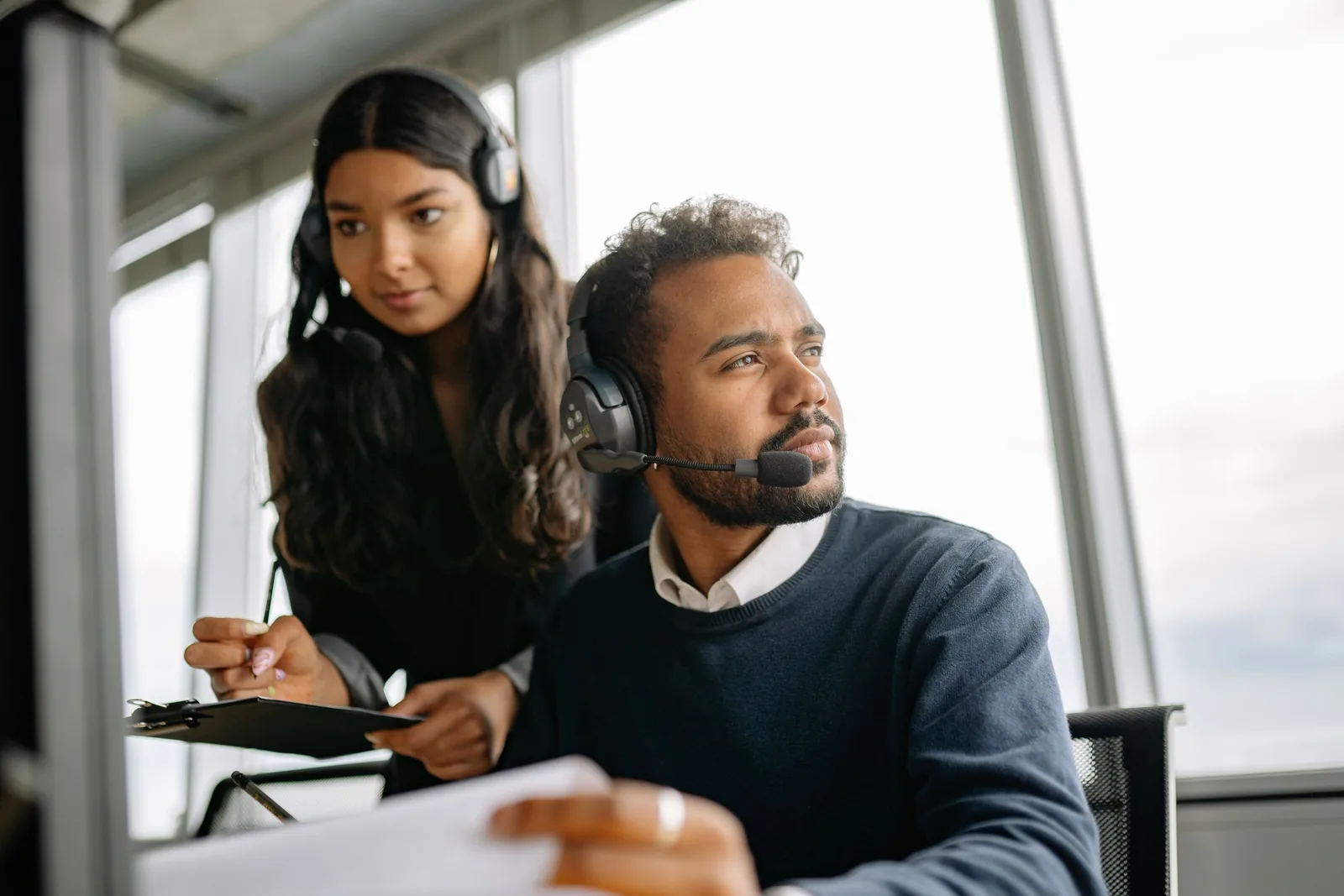 Zwei Mitarbeitende mit Headsets arbeiten konzentriert am Computer