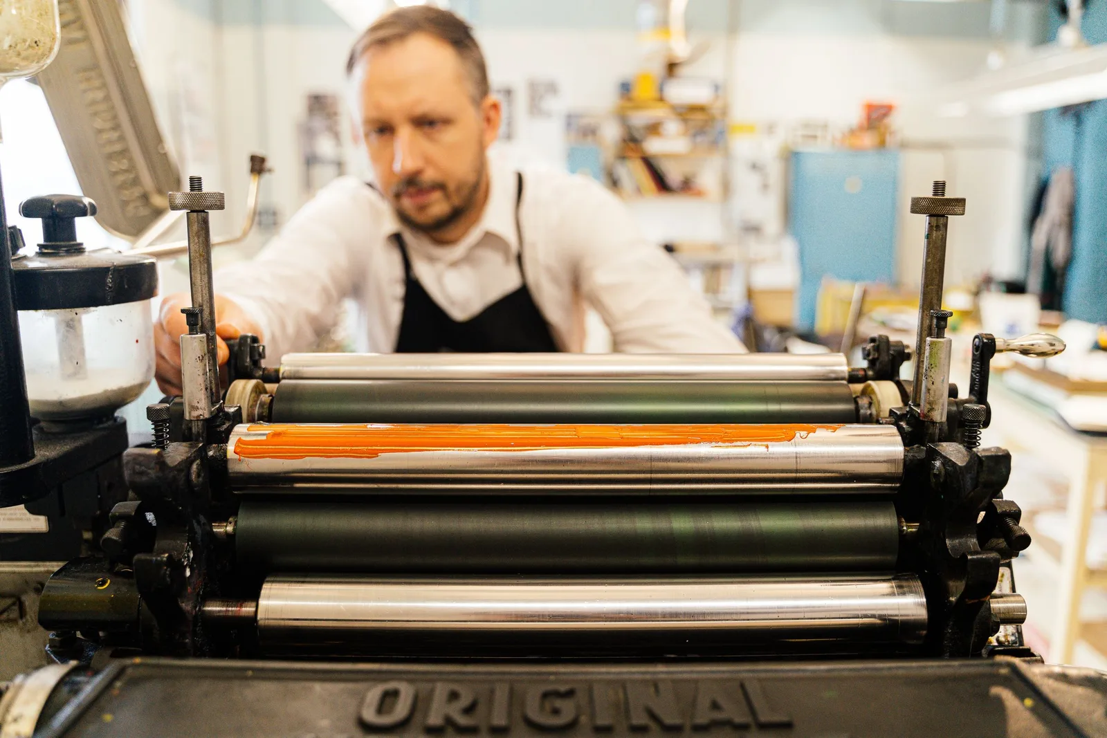 Drucker bedient eine Druckmaschine in einer hellen Werkstatt