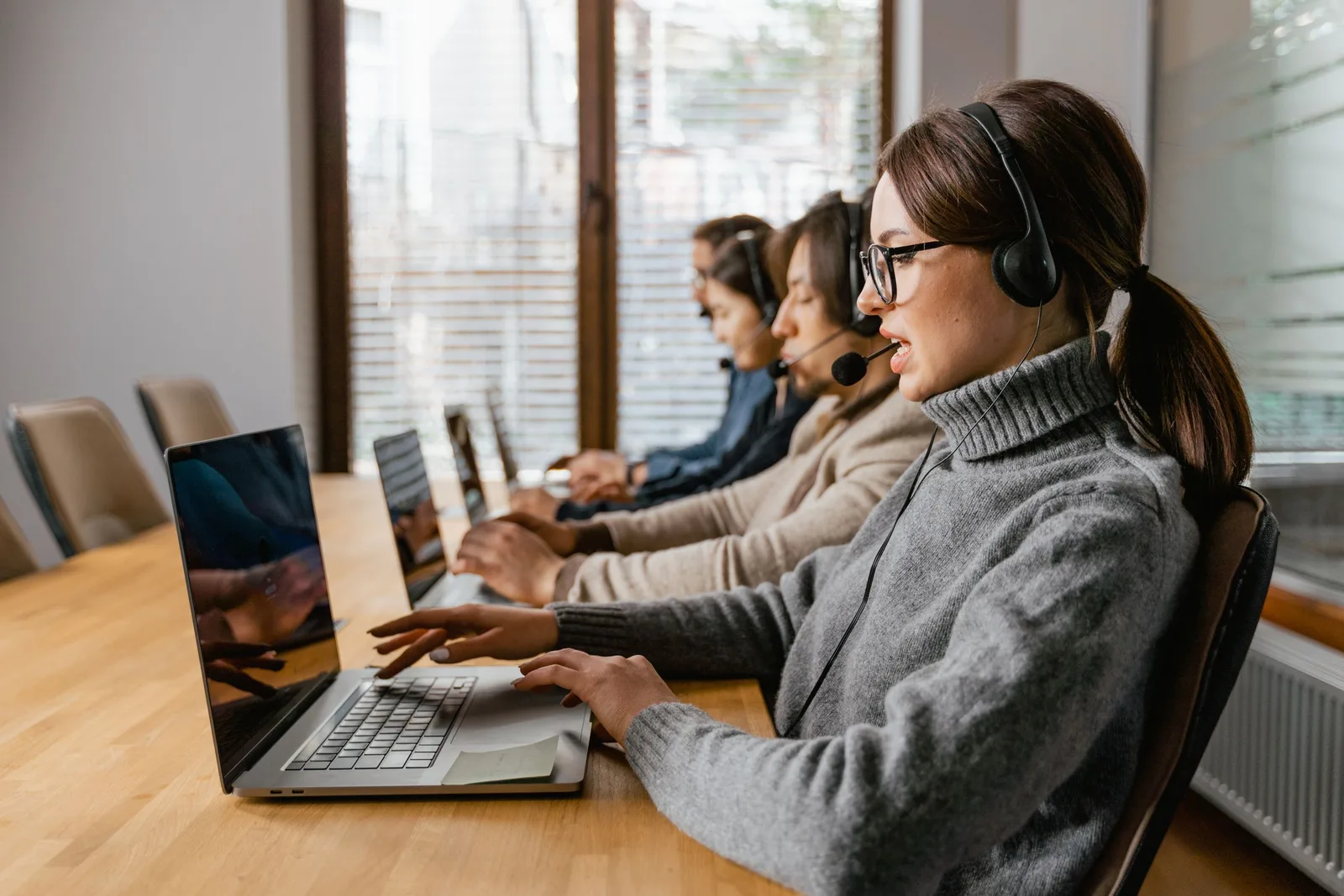 Mitarbeitende mit Headsets und Laptops in einem modernen Büro