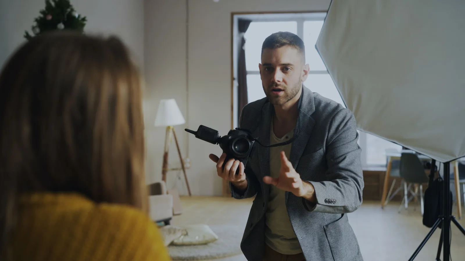 Fotograf gibt im Studio Anweisungen, im Hintergrund Studiolicht