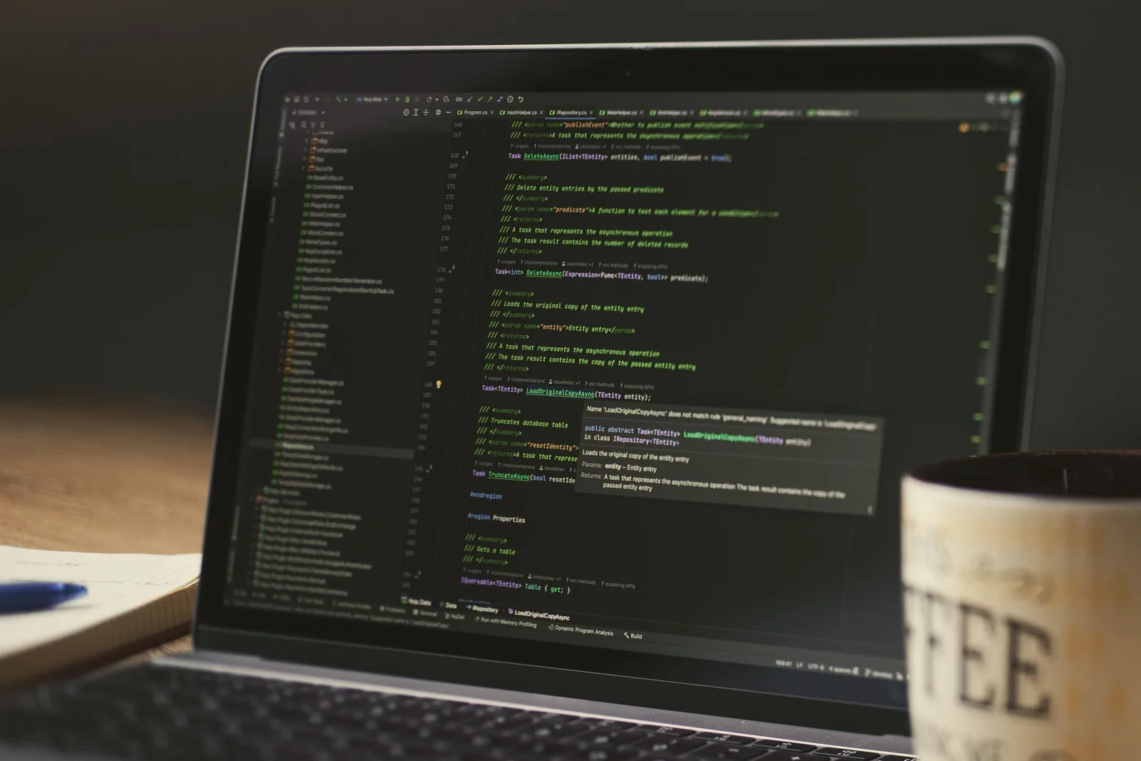 Laptop mit Programmcode im Editor, daneben eine Kaffeetasse
