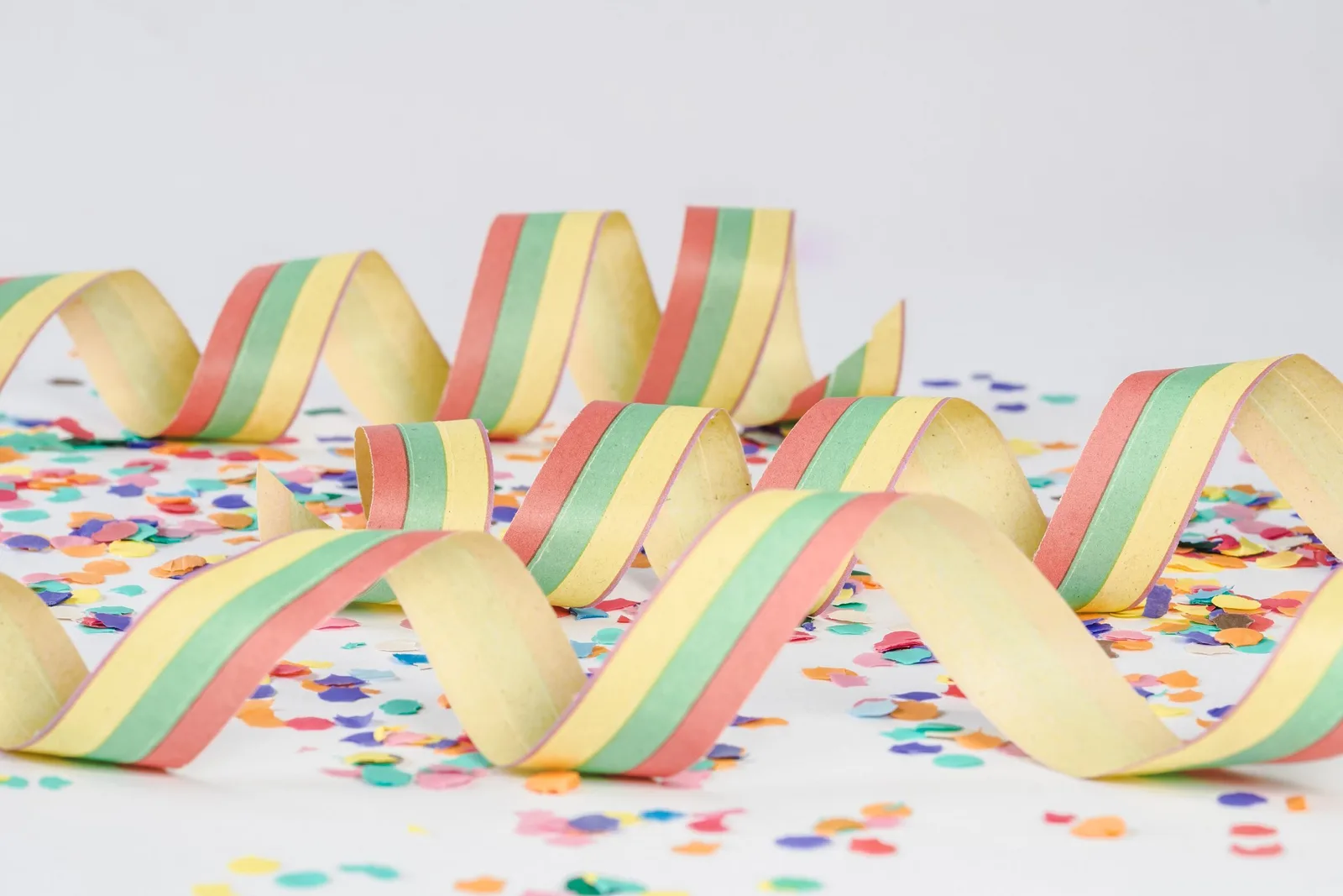 Bunte Luftschlangen und Konfetti auf hellem Grund