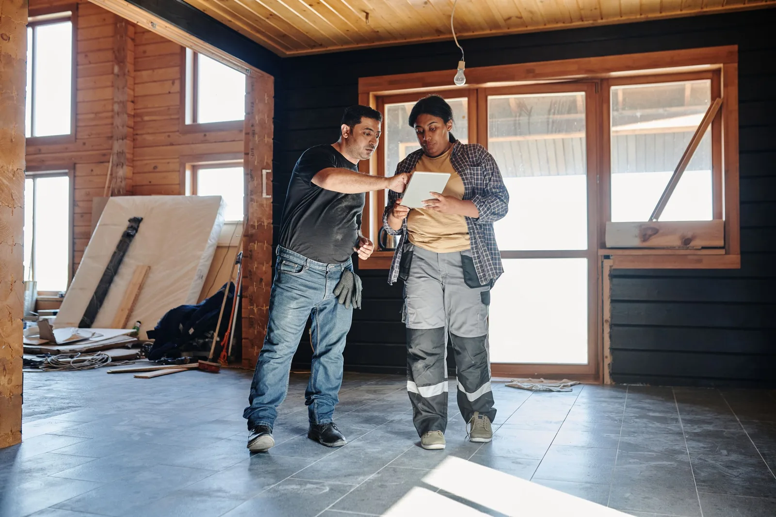 Zwei Handwerker besprechen auf einer Baustelle Pläne auf einem Tablet