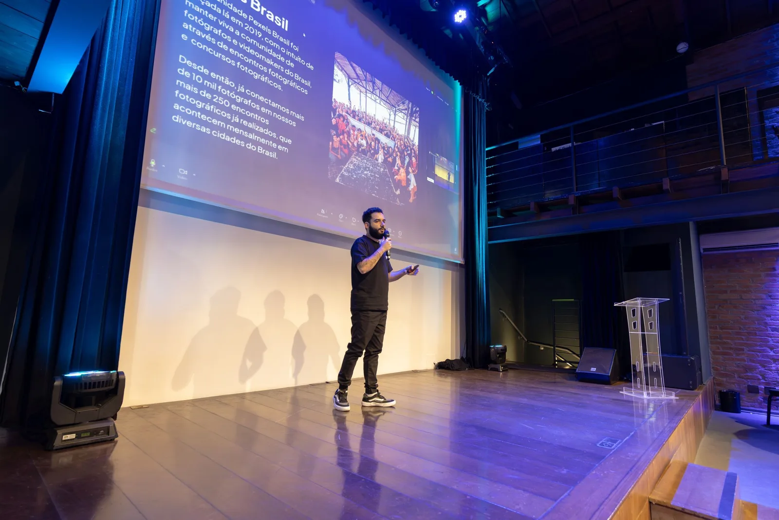 Redner präsentiert auf einer Konferenzbühne vor einer Leinwand