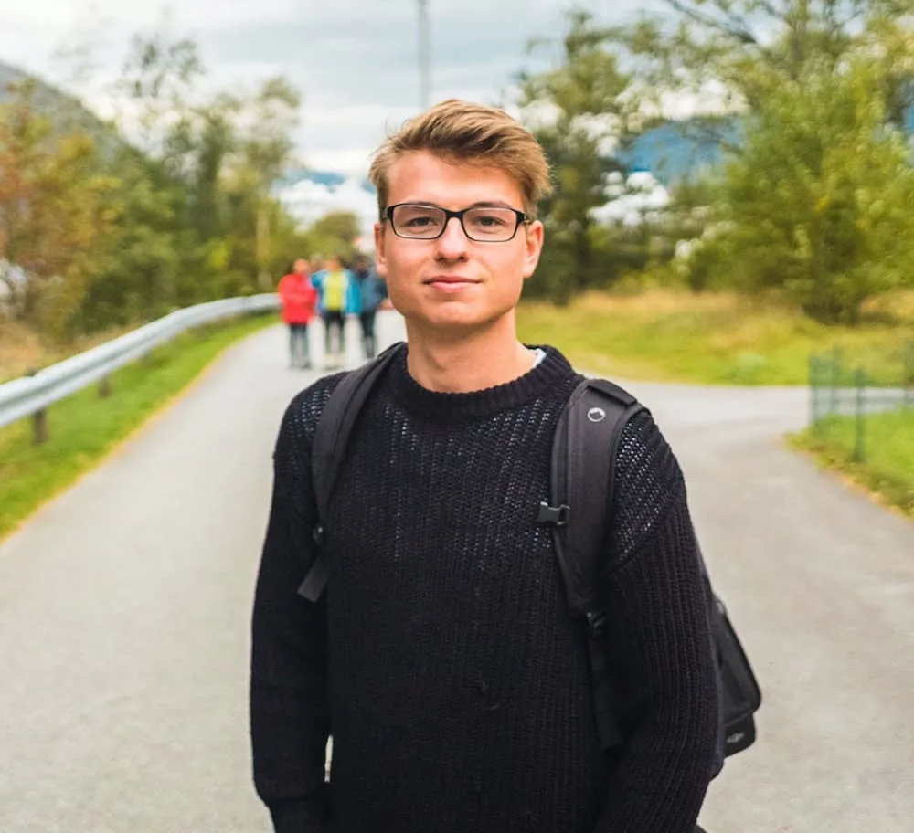 Philipp Posmyk mit Brille und Rucksack auf einem Weg im Grünen